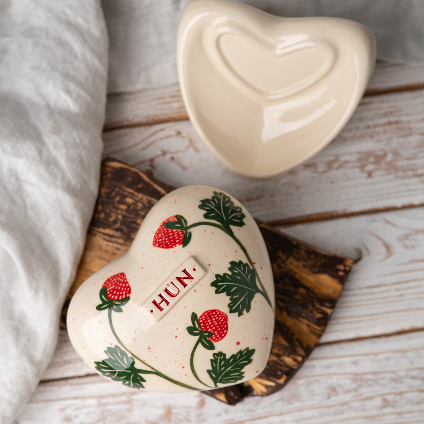 Top view of the heart-shaped urn showing the detailed red strawberries and green leaf illustration.