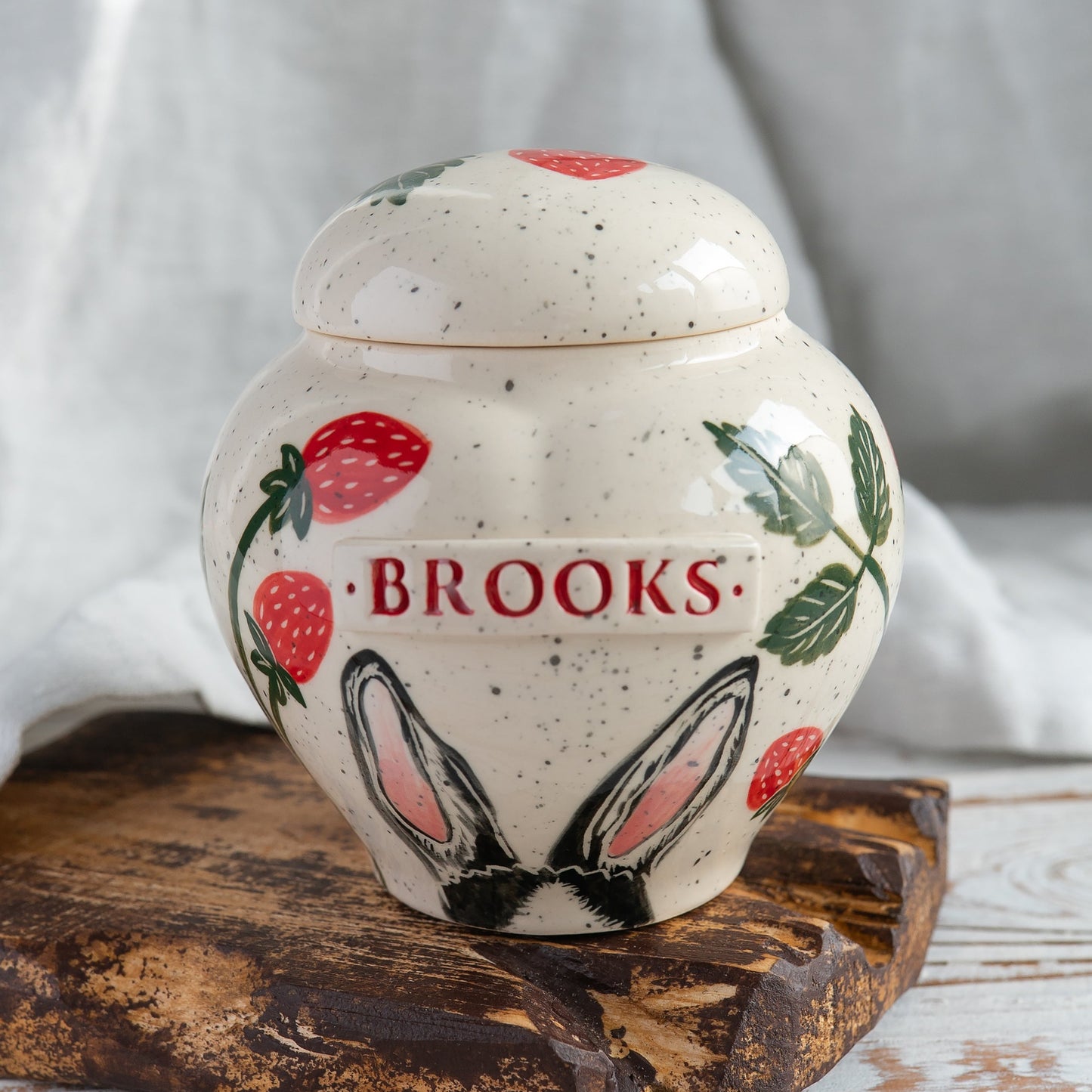 Hand-painted ceramic heart-shaped rabbit urn with strawberry folk-art pattern and delicate painted bunny ears on the body.