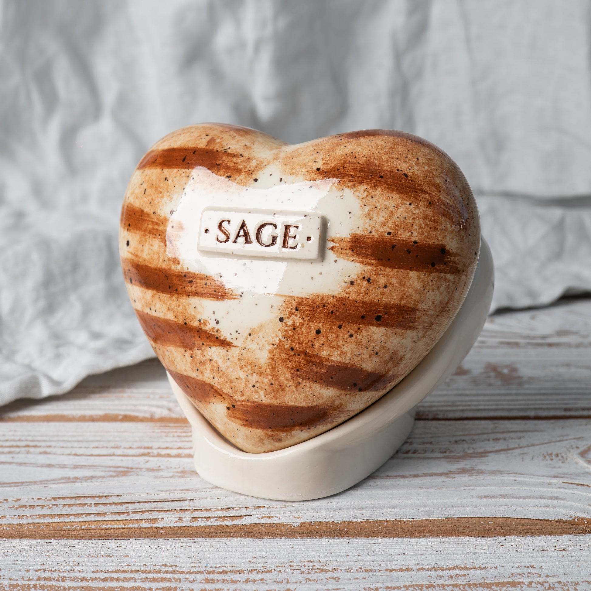 Side view of the heart-shaped ginger cat memorial urn, highlighting the elegant ceramic stand and smooth finish.