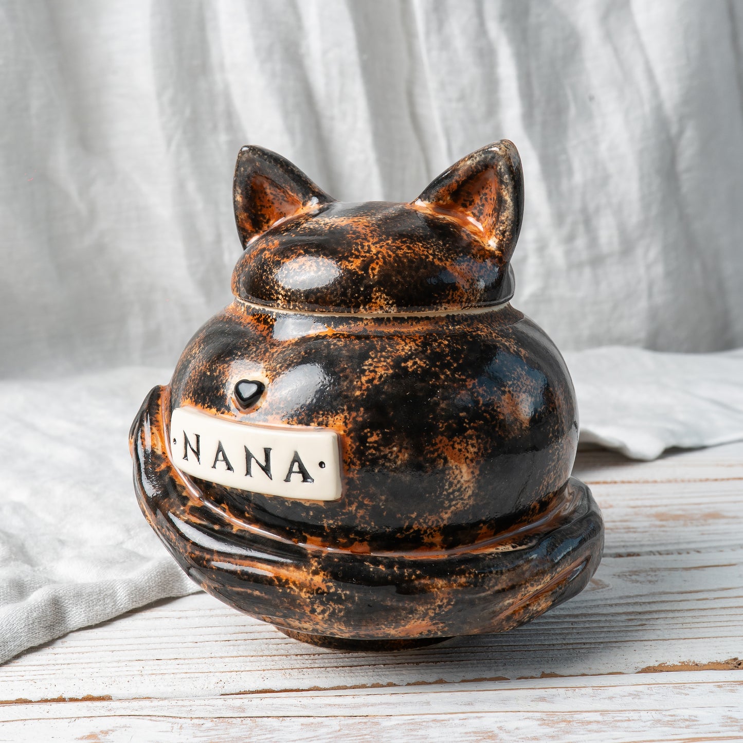 Side view of hand-painted tortie cat ceramic pet memorial urn showing mottled fur pattern and tail details