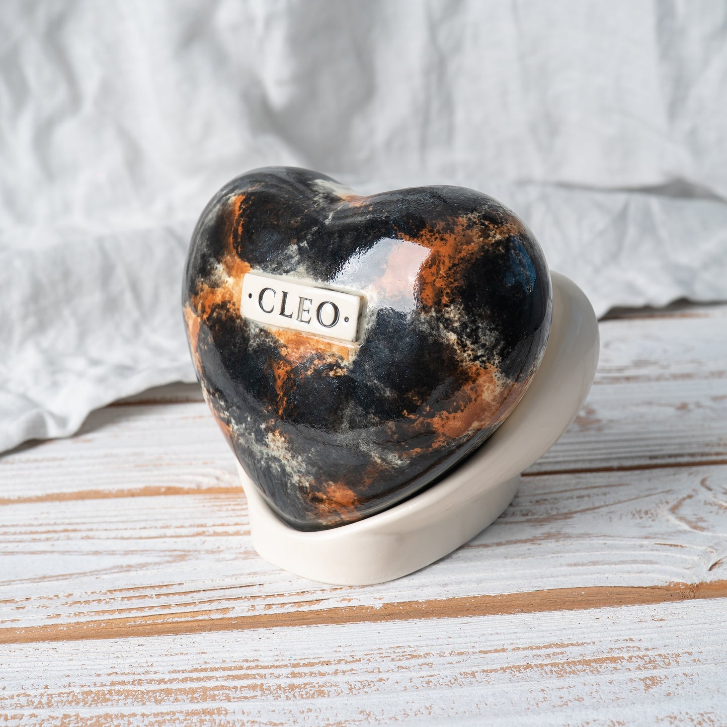 Side profile view of the heart-shaped ceramic tortoiseshell cat urn, highlighting the smooth glaze and unique shape.