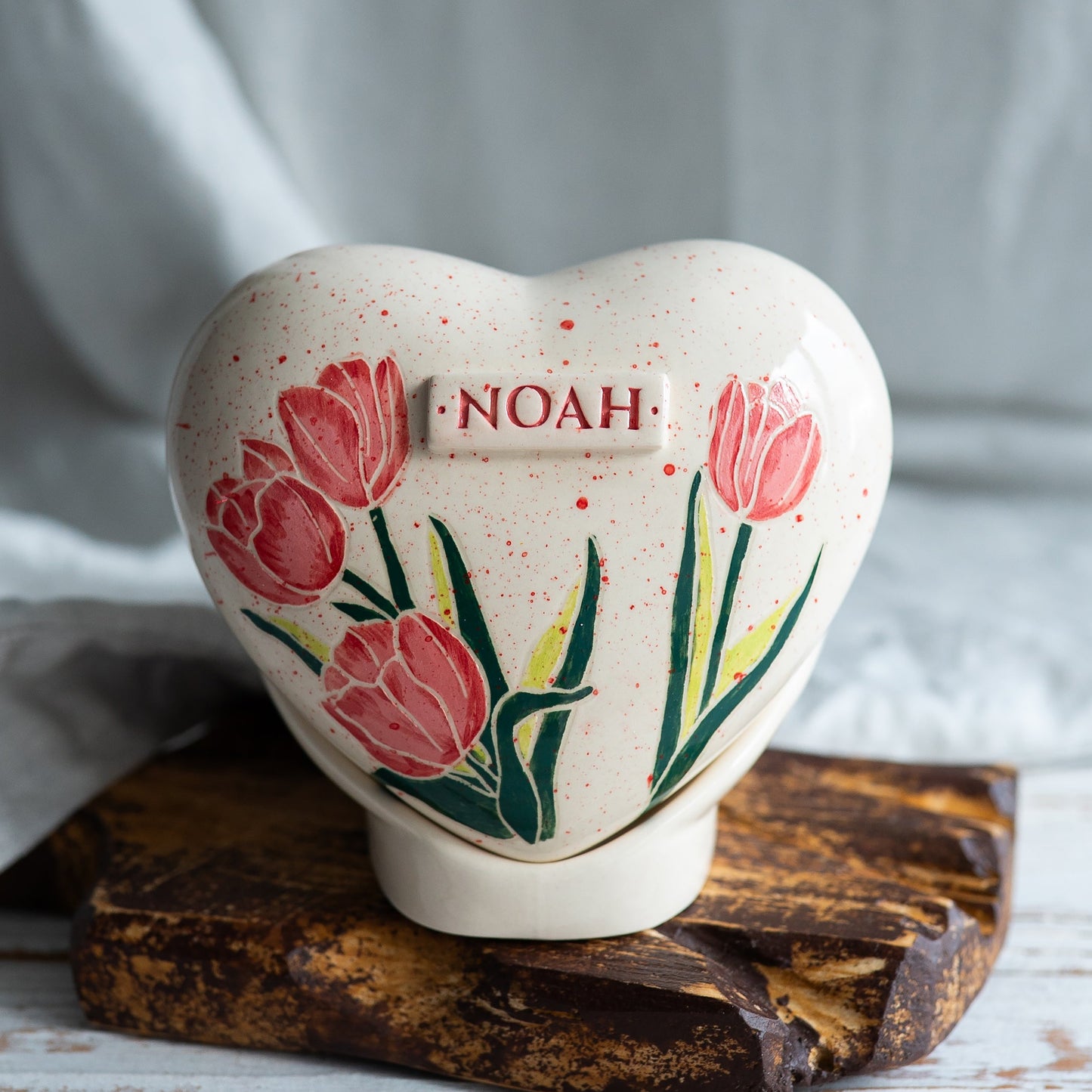 Hand-painted heart-shaped ceramic urn with elegant tulip flowers and a matching stand for human or pet ashes.