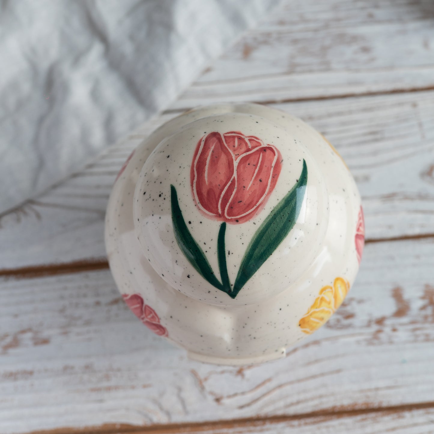 Top-down view of the closed heart-shaped sharing urn lid, featuring hand-painted pink and yellow tulips
