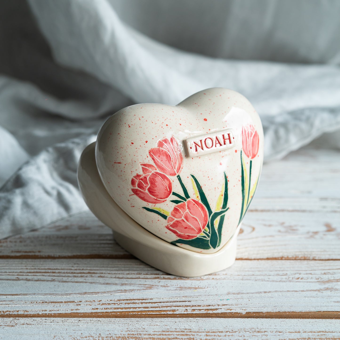 Side profile of the tulip memorial urn on its stand, highlighting the smooth glaze and handmade artisan quality.