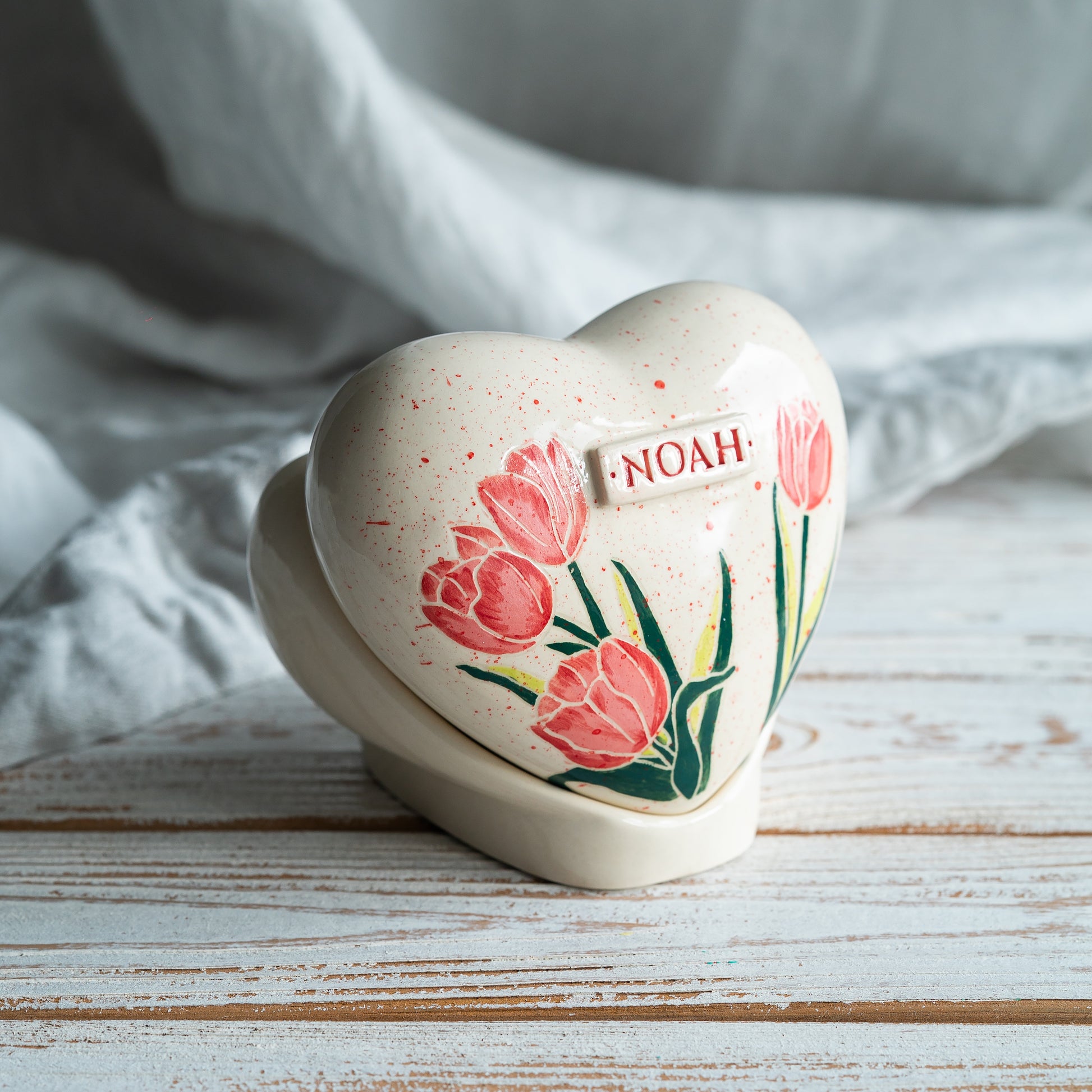 Side profile of the tulip memorial urn on its stand, highlighting the smooth glaze and handmade artisan quality.