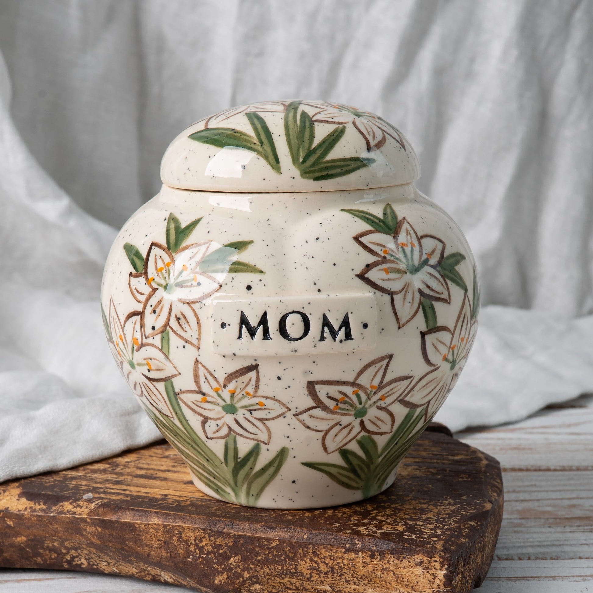 White lily heart-shaped ceramic urn for ashes with delicate hand-painted flowers front view