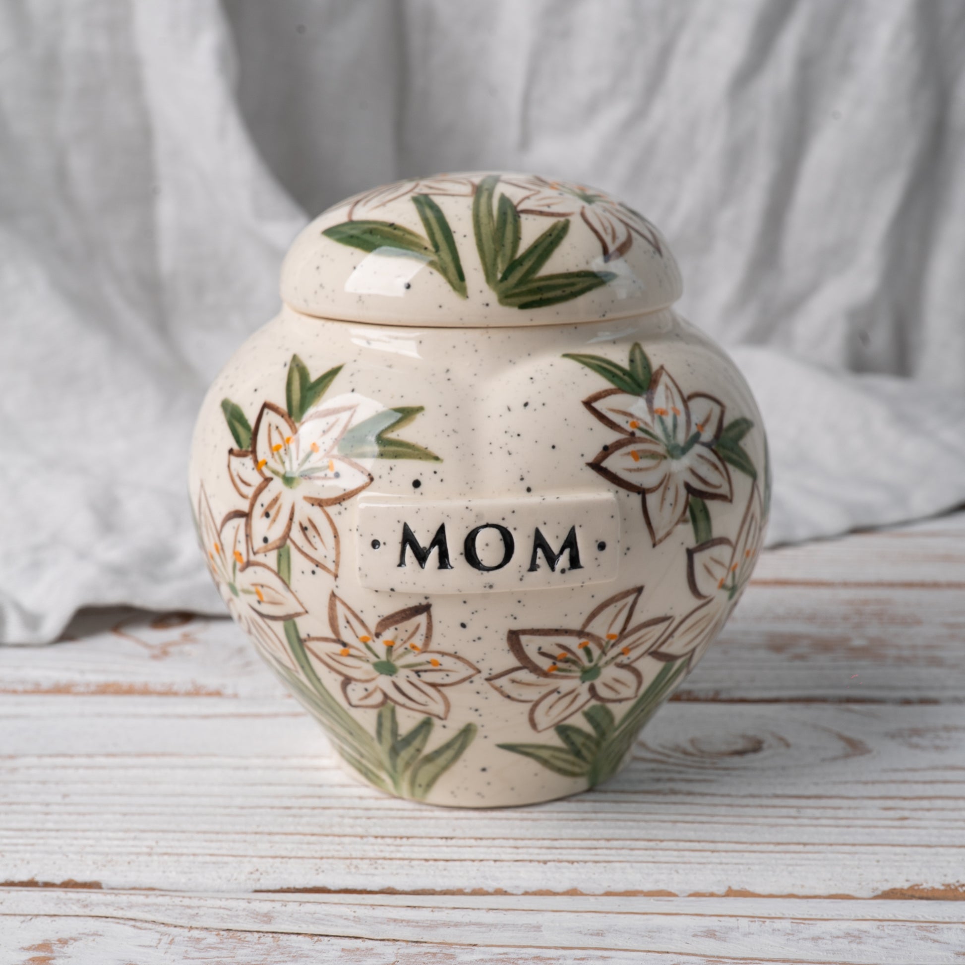 White lily heart-shaped ceramic urn for ashes with delicate hand-painted flowers front view