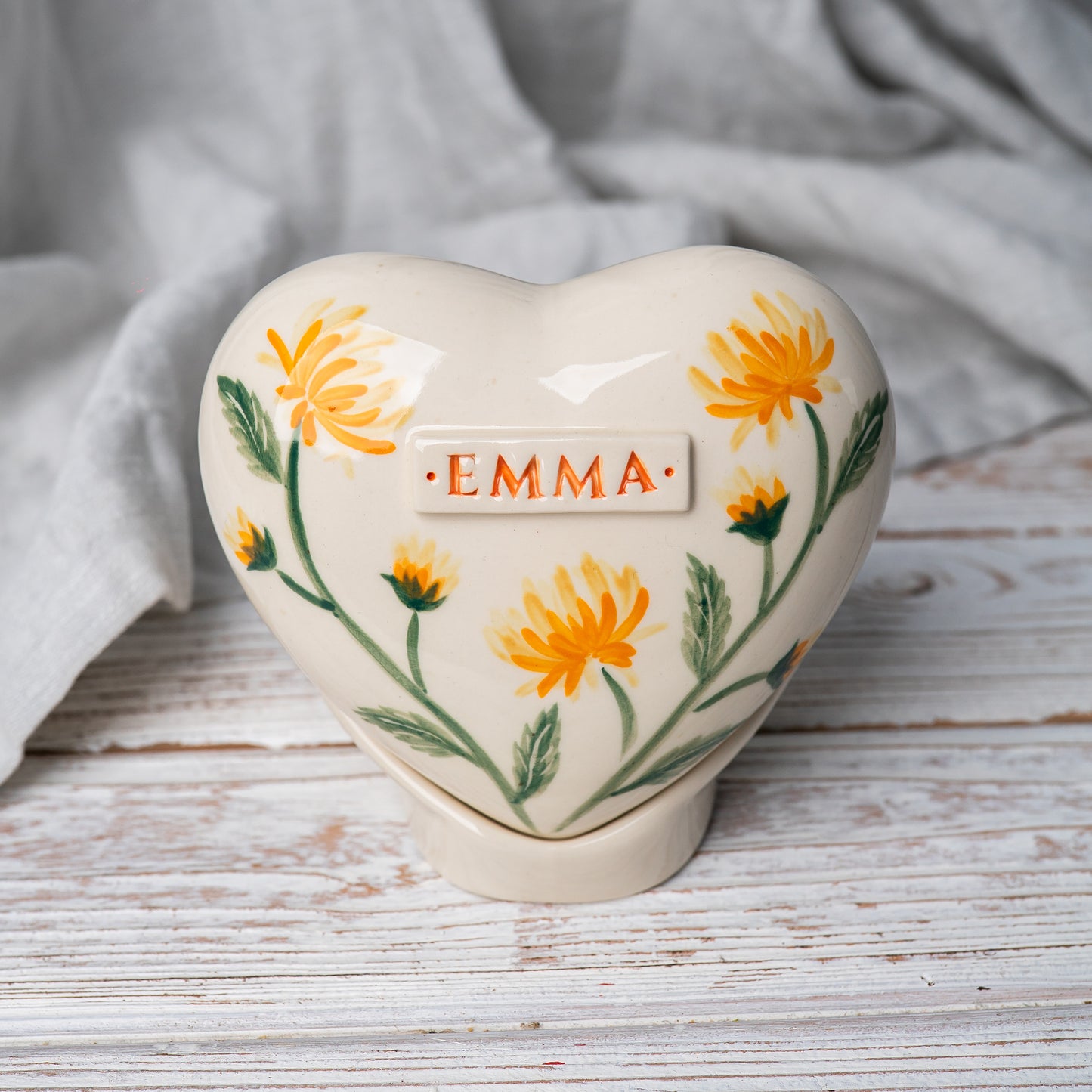 Hand-painted heart-shaped ceramic urn with yellow chrysanthemums and a matching stand for human or pet ashes.