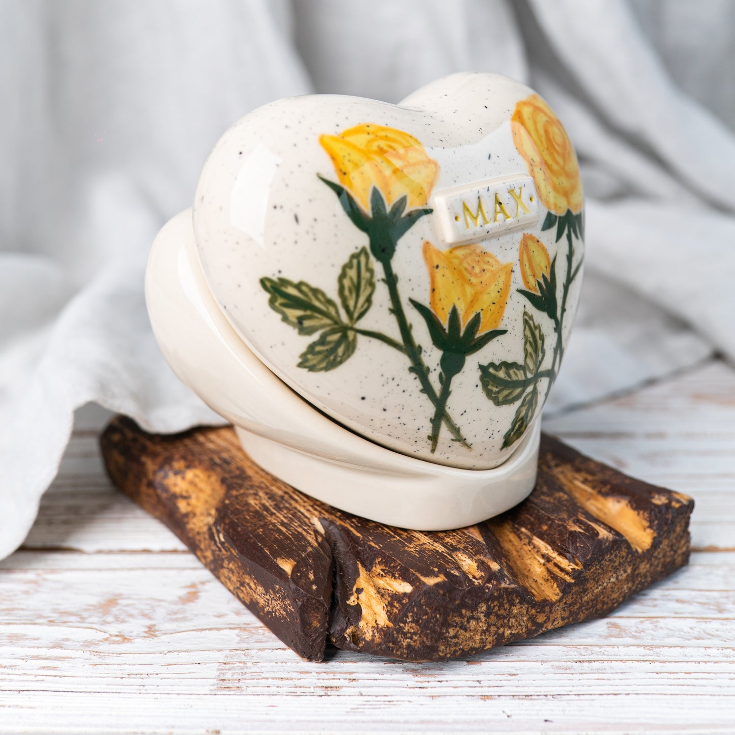 Side profile of the yellow rose memorial urn on its stand, highlighting the smooth glaze and handmade quality.