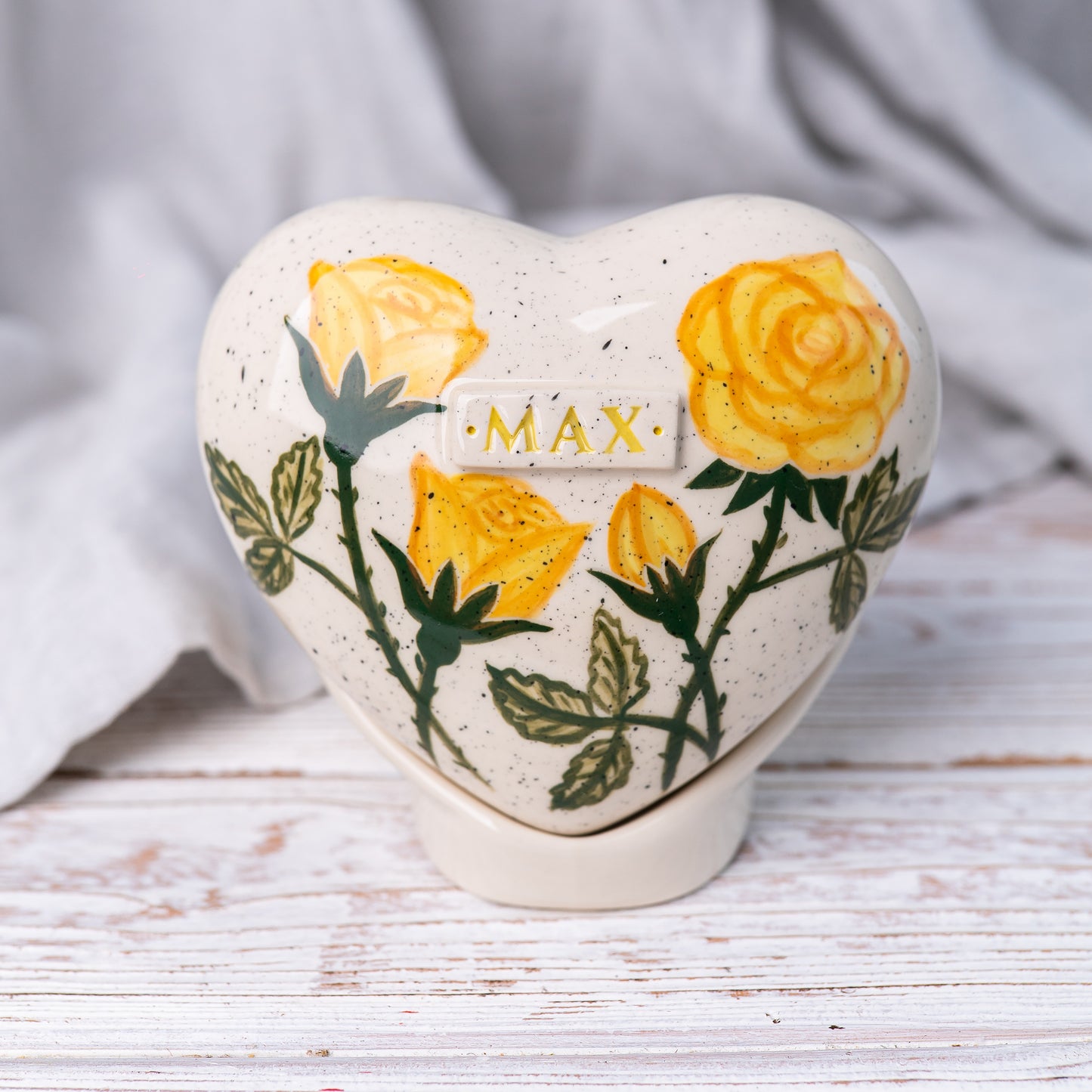 Hand-painted heart-shaped ceramic urn with yellow roses and a matching stand for human or pet ashes.