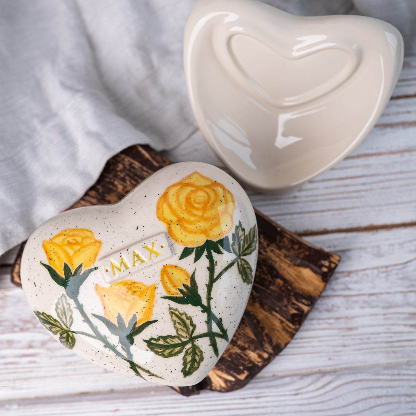 Top view of the ceramic heart urn, showing the detailed yellow rose petals and green leaf accents.