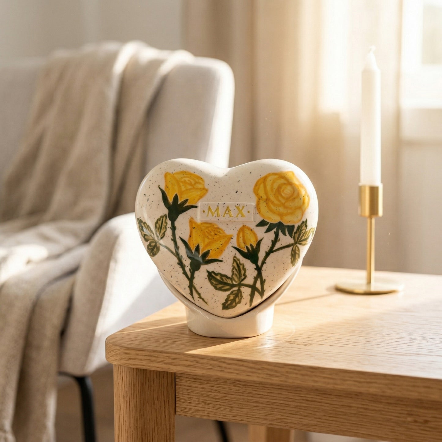 A warm home memorial display with a yellow rose heart urn on a white shelf next to a small candle.